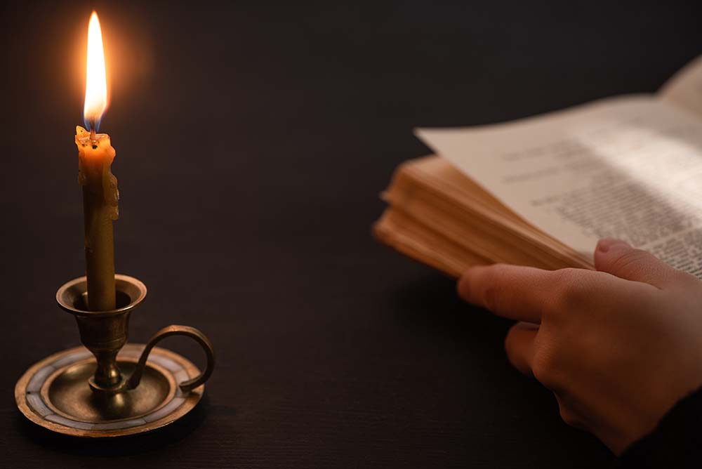 a woman holding a bible in candlelight