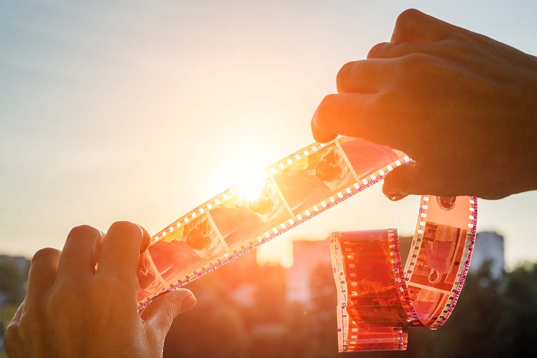 someone holding up film negatives to the sunlight